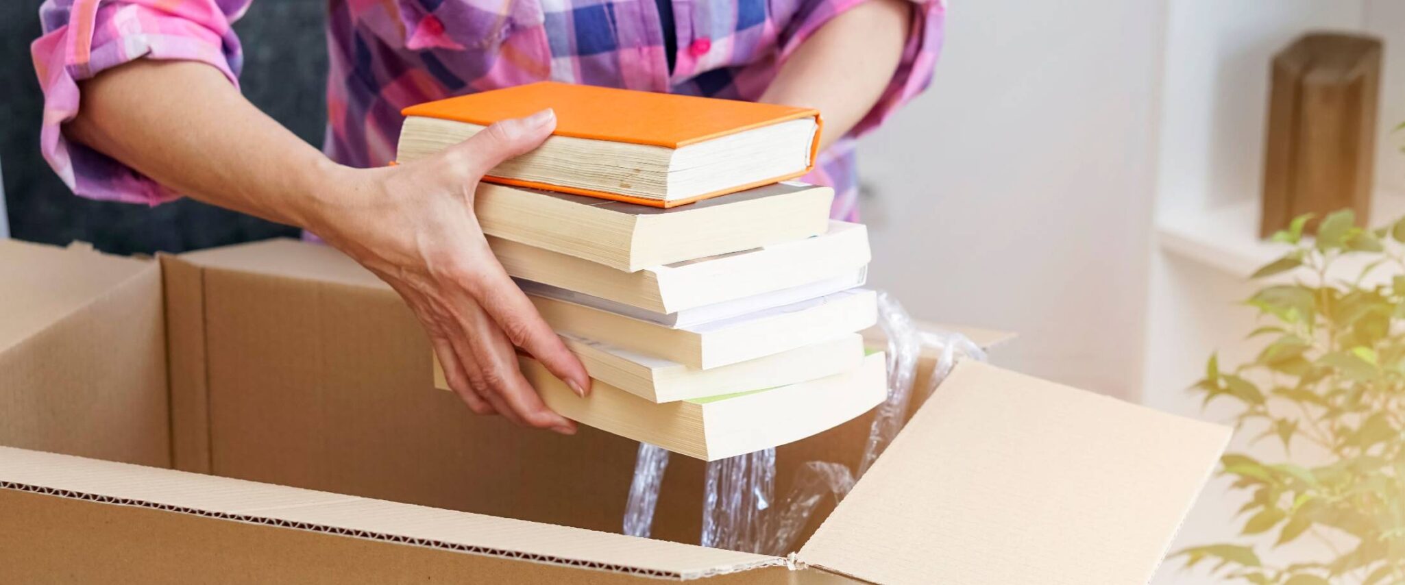 woman putting a stack of books into a box