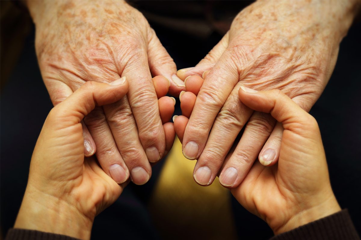 Close up of a senior woman's hands held by a younger woman's hands