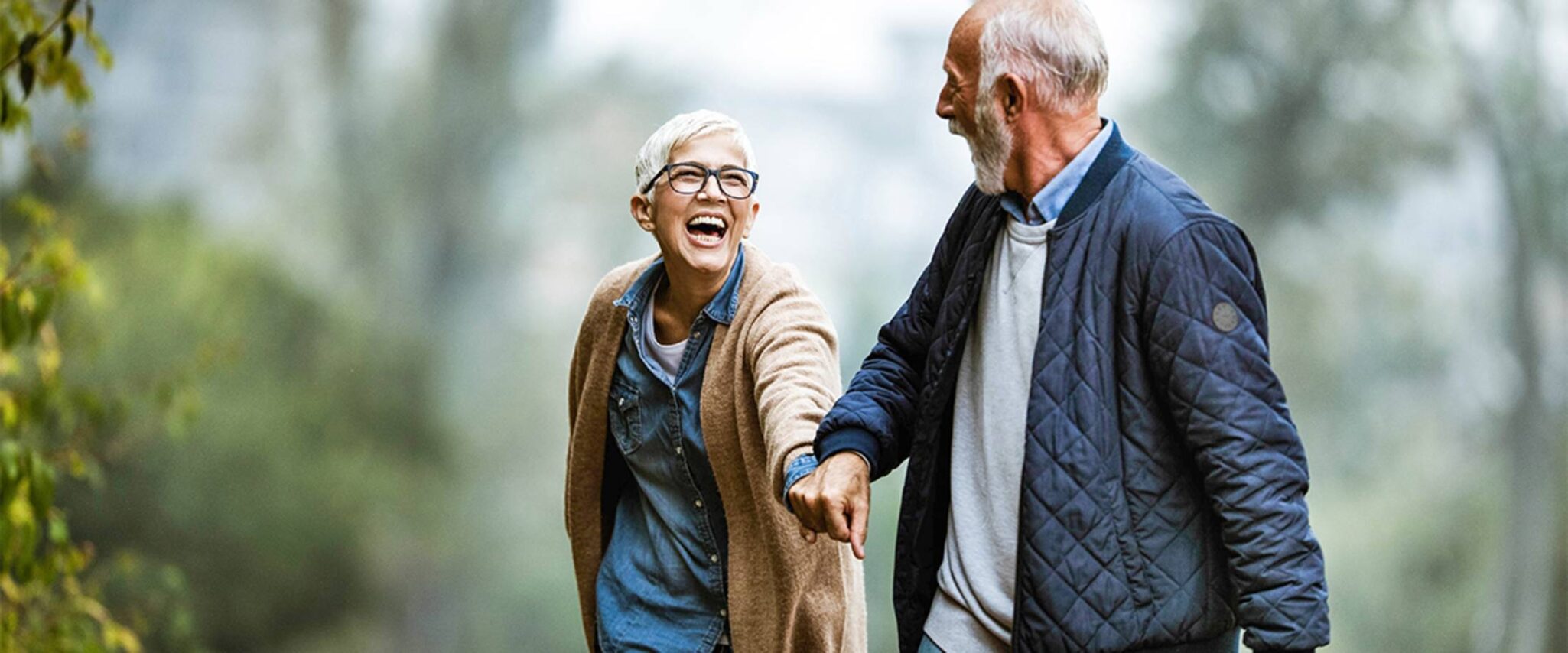 senior couple holding hands as they walk outside and laugh