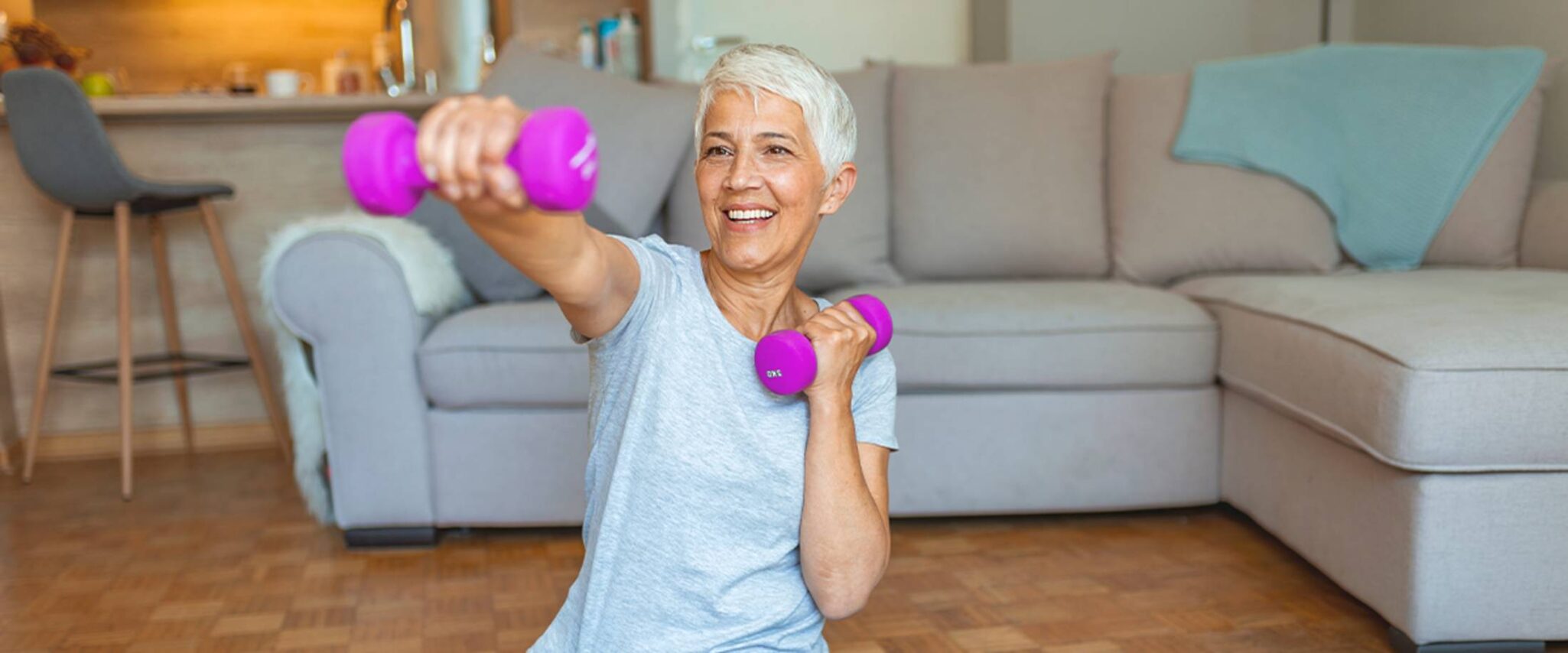 A senior woman works out with pink free weights
