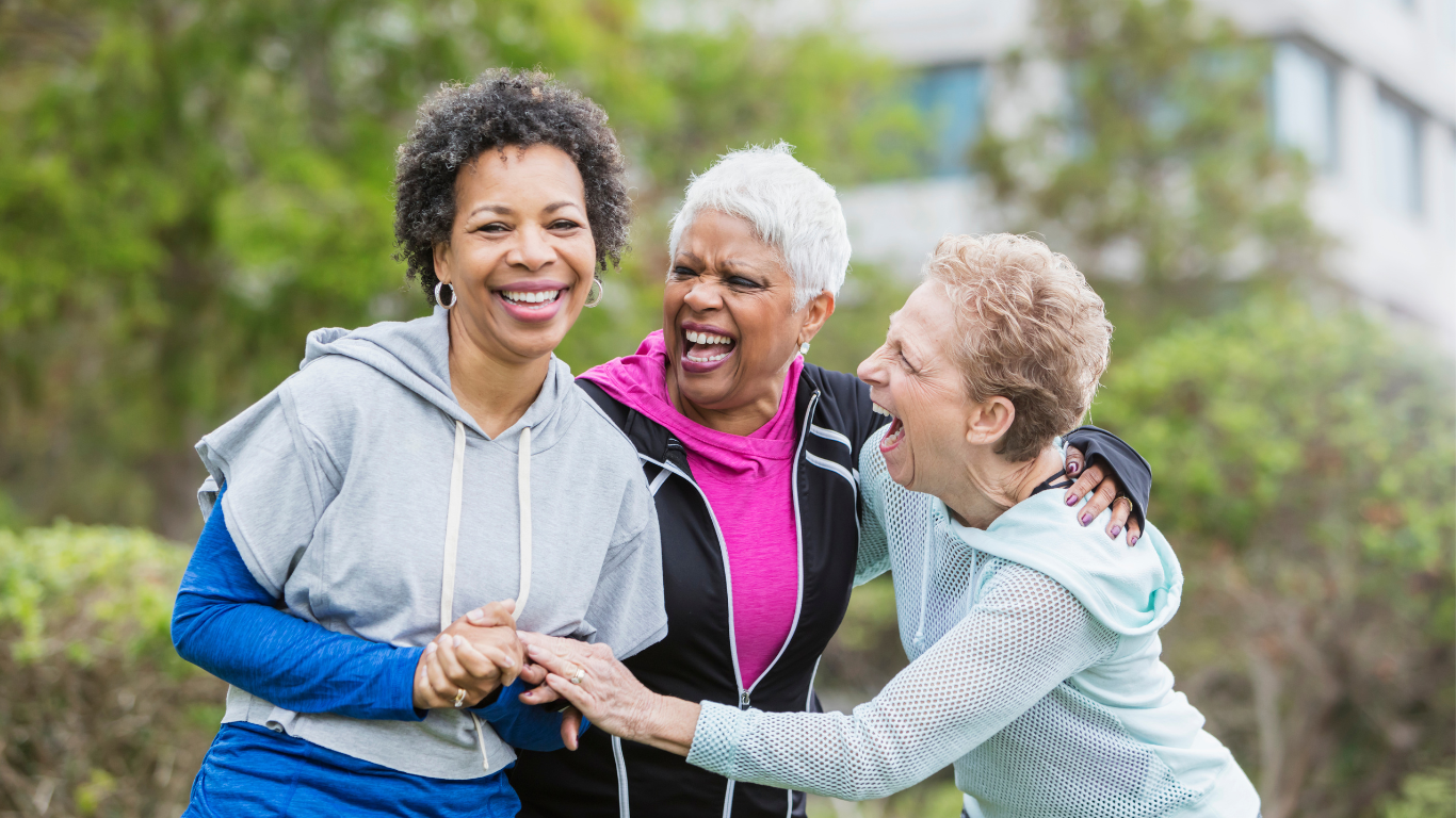 Three smiling senior friends laughing outdoors