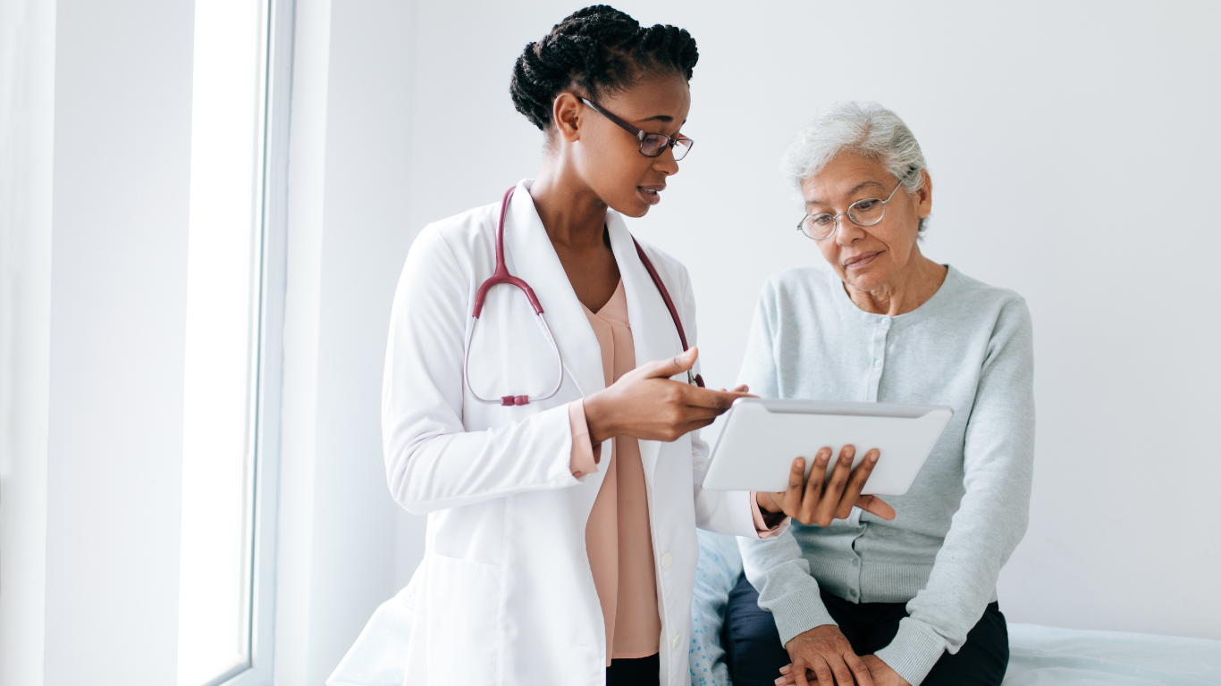 Female healthcare worker and senior woman looking at tablet