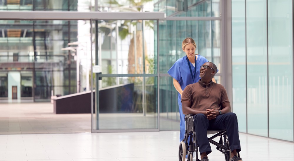 Female nurse wheeling happy senior man in wheelchair