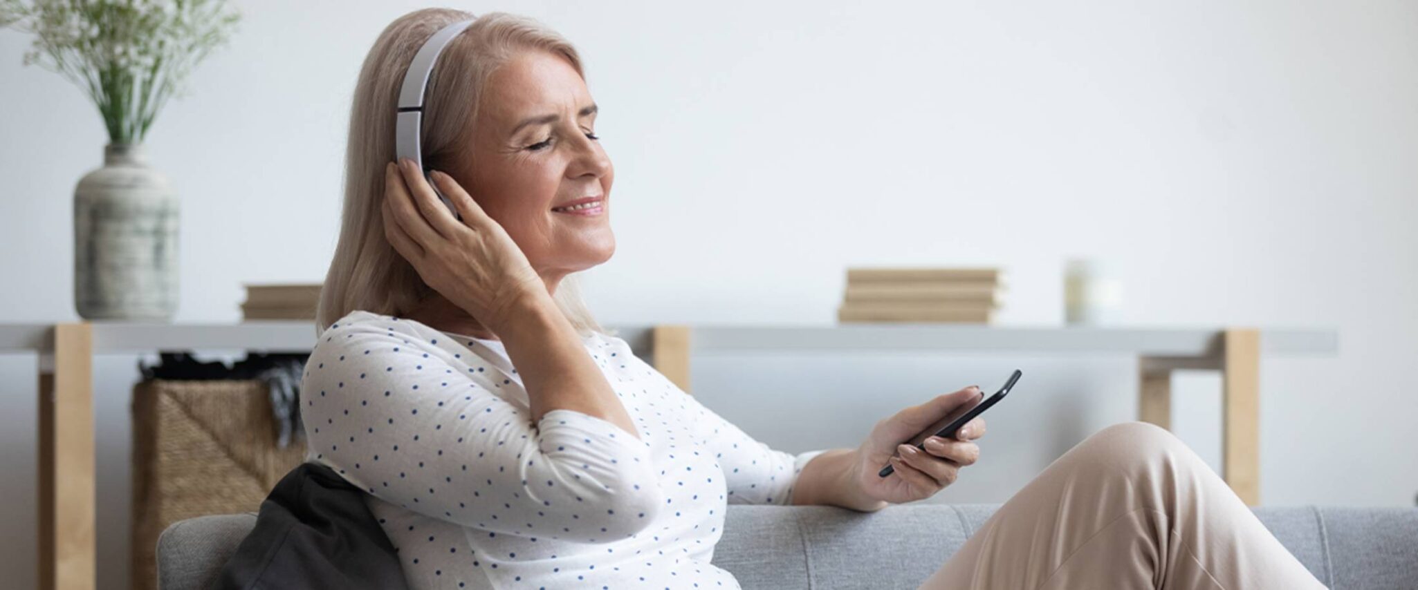 senior using headphones to enjoy music on her phone