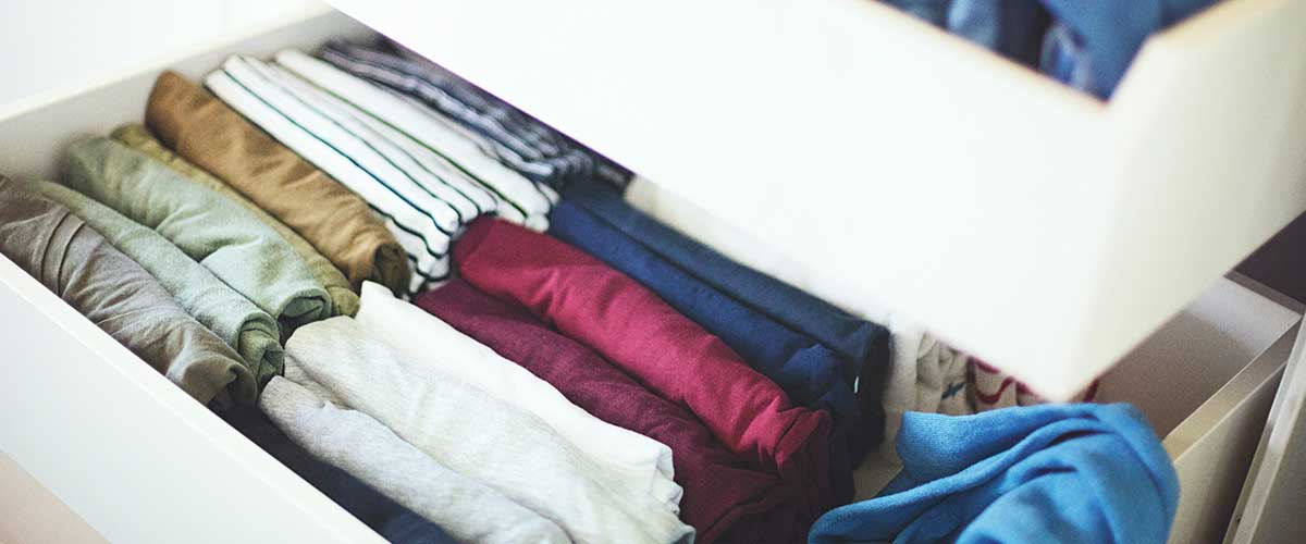 drawer of a dresser with shirts neatly folded