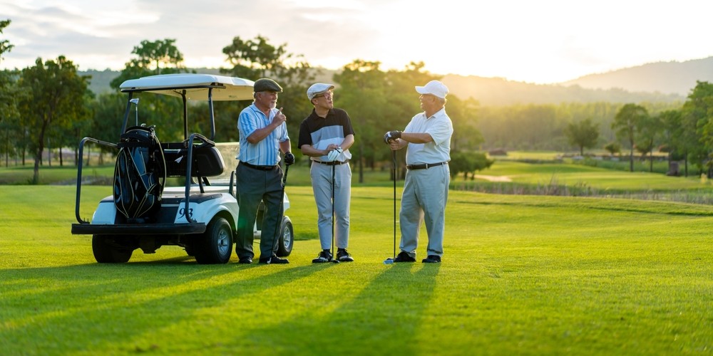 A group of senior men visit while playing golf.