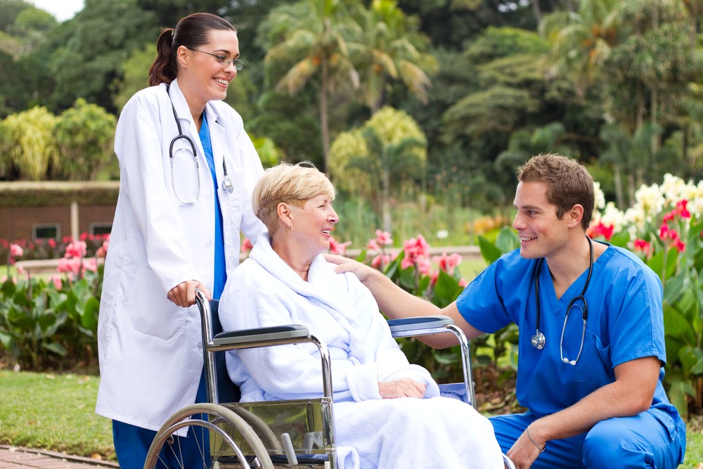 male doctor talking to senior patient in hospital garden