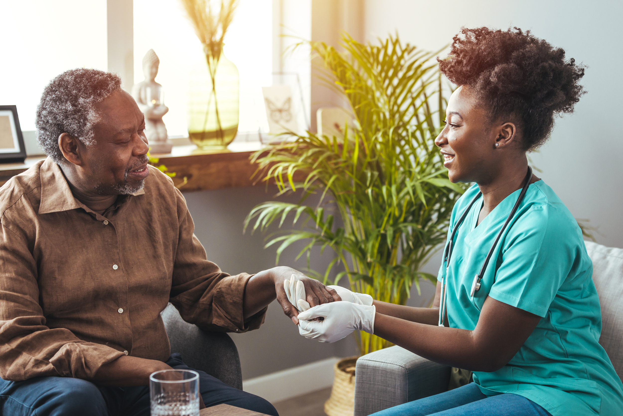 Female healthcare worker holding senior man's hand
