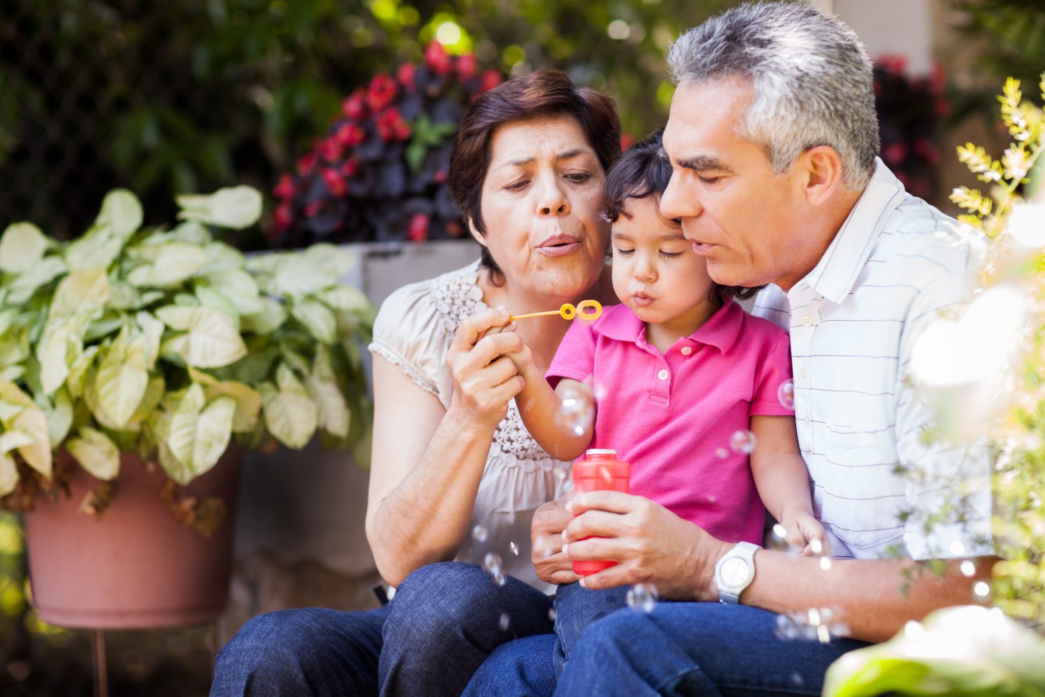 Grandparents blowing bubbles with granddaughter